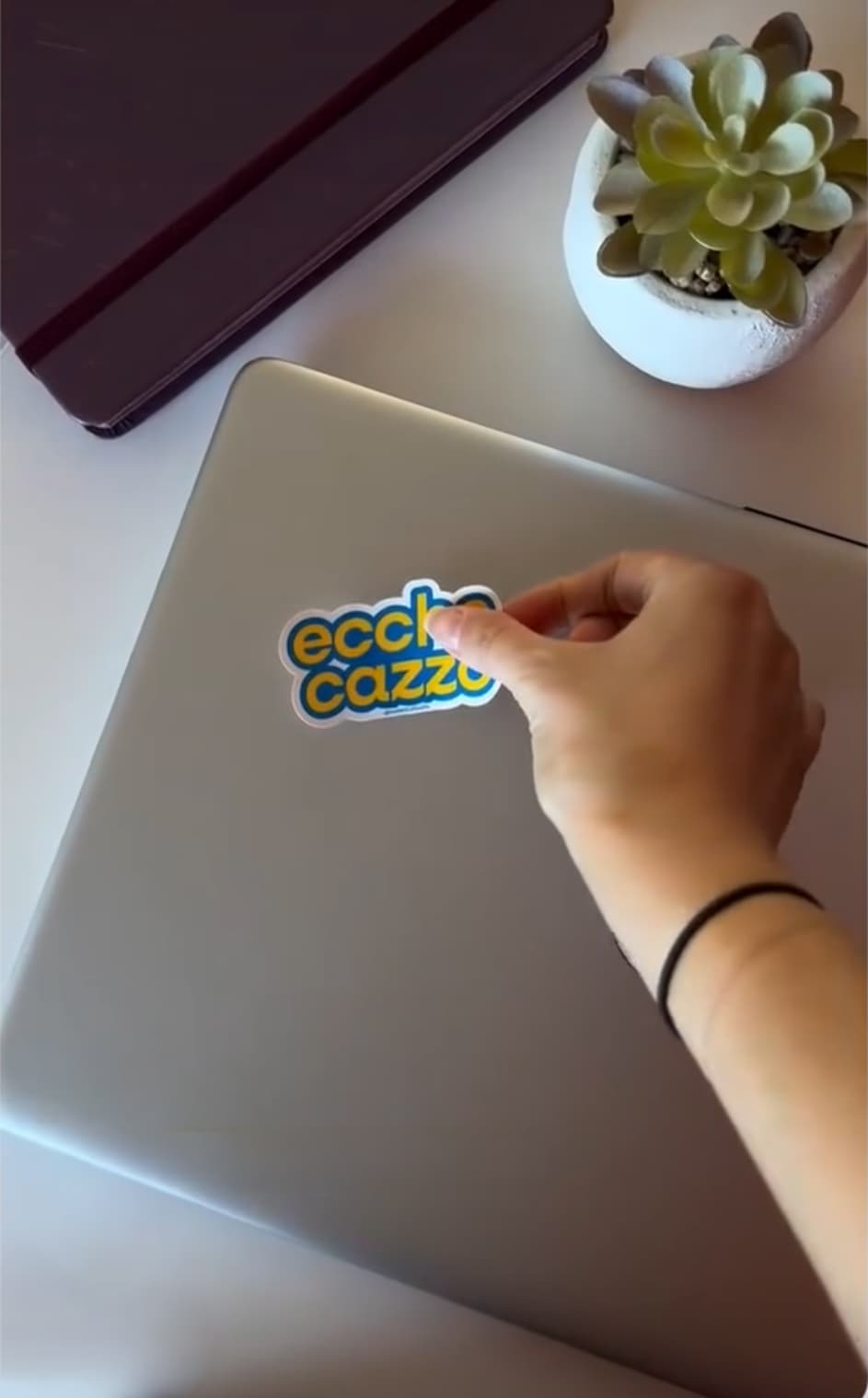 Hand putting a colourful sticker on a laptop lid