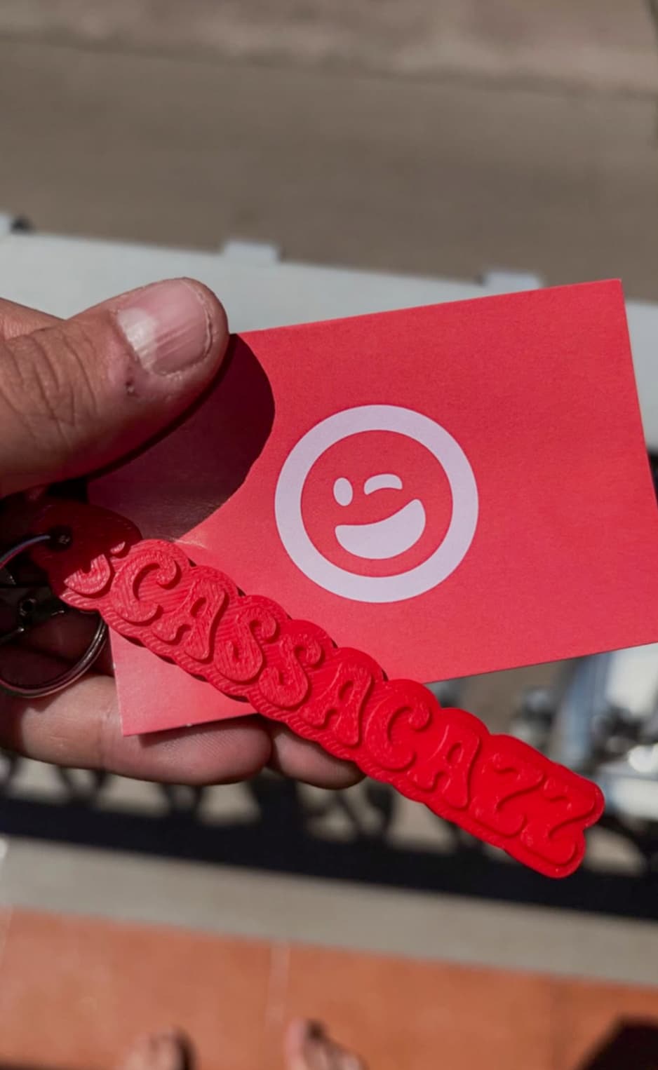 Red raised-letter keychain held in front of a Notami card