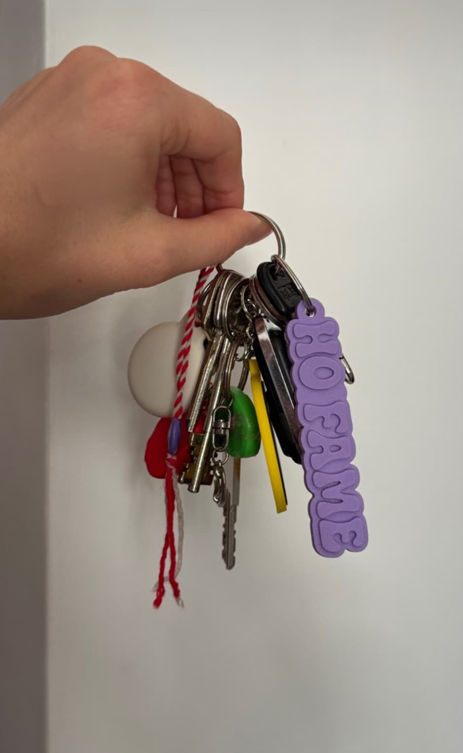 Lilac keychain hanging from a set of keys held in a hand