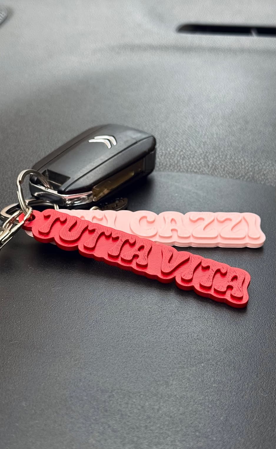 Red and pink keychains beside a car key